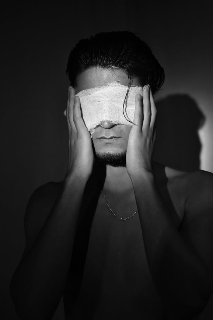 Terapias Artistic black and white portrait of man with covered eyes conveying emotion.